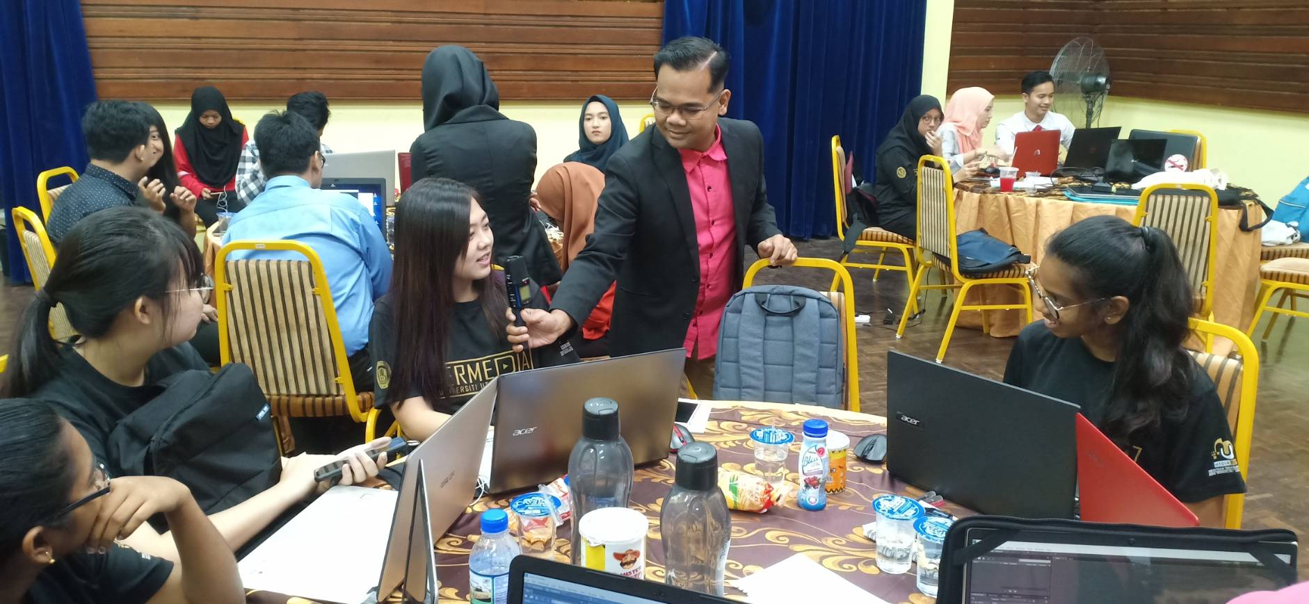 Young participants using laptops and sharing ideas with a facilitator during a workshop